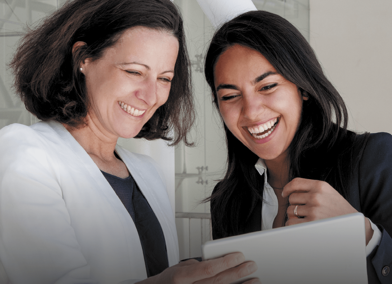 duas colaboradoras alegres a concultar um ipad