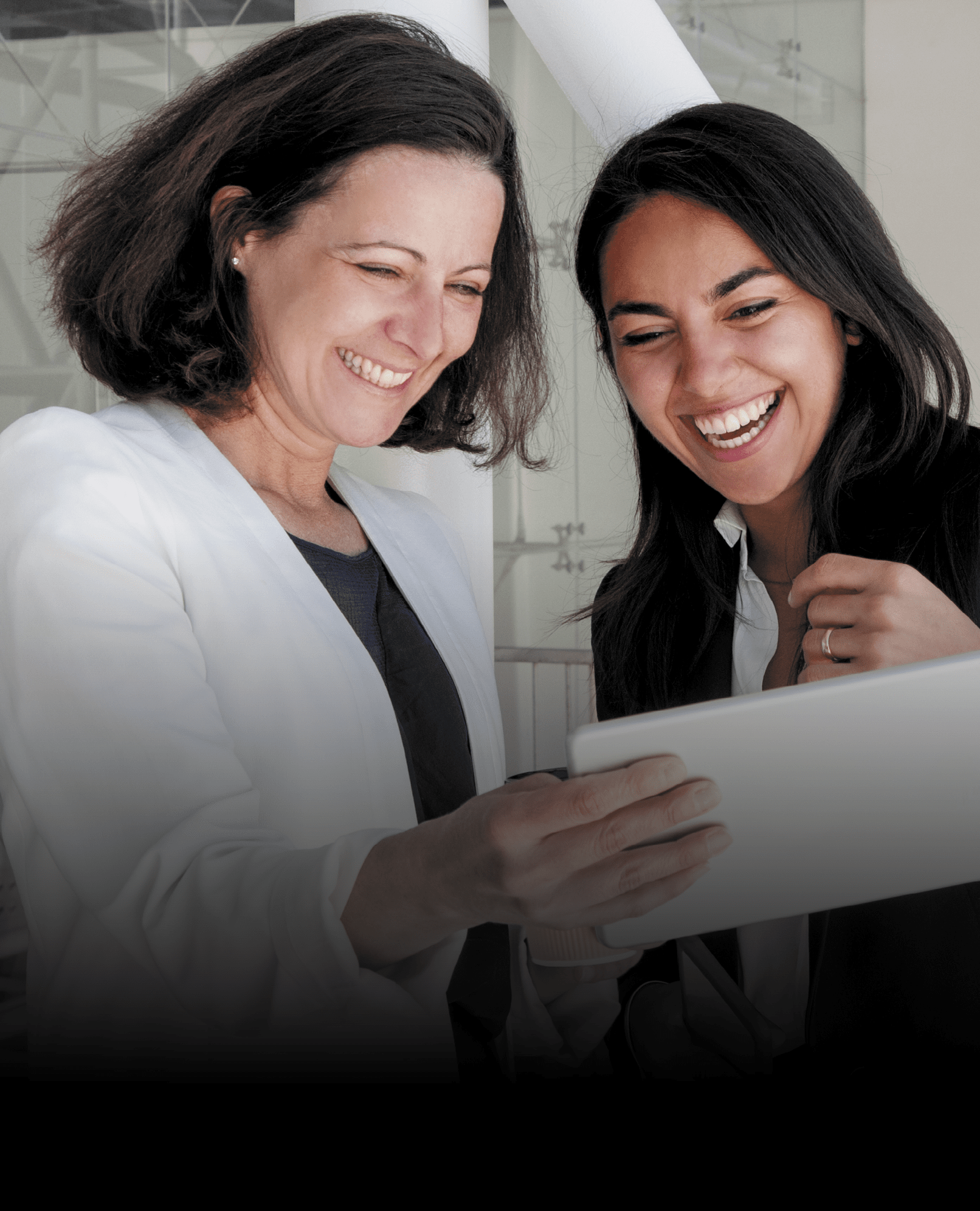 duas colaboradoras alegres a concultar um ipad